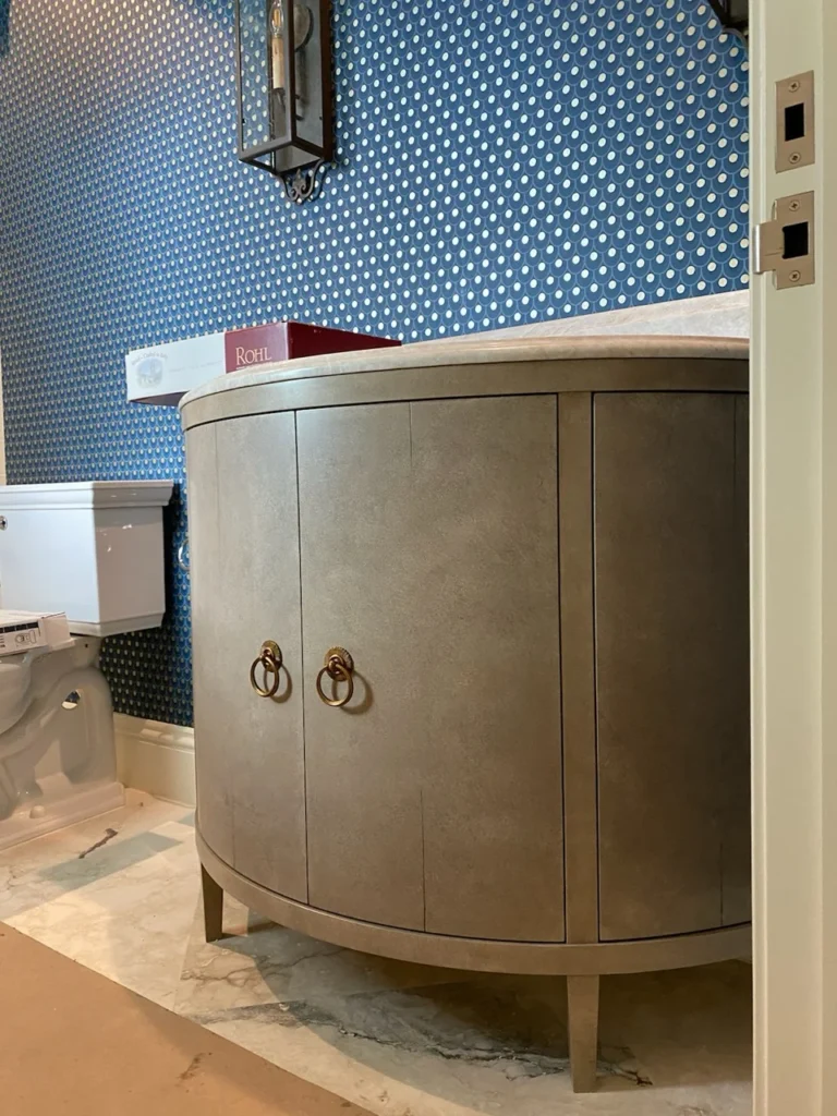 Curved metallic powder room vanity with ring pulls and furniture-style legs