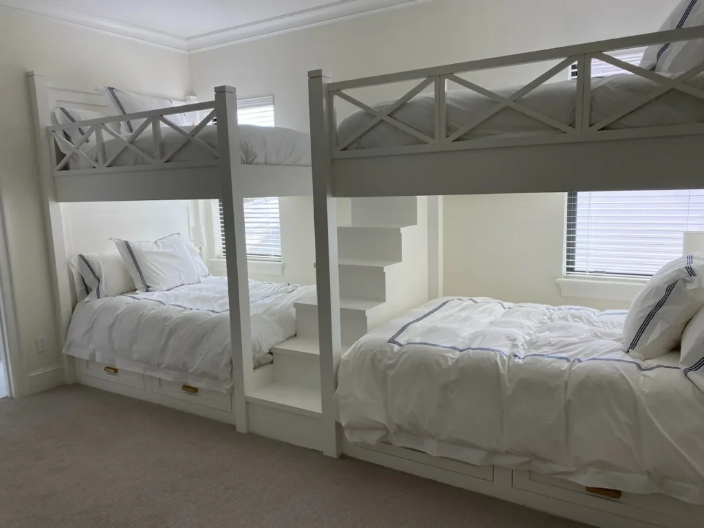 Pair of white custom bunk beds with integrated stairs, rails and drawer storage