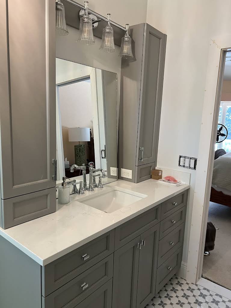 Gray bathroom vanity with mirrored storage towers, quartz counter and integrated lighting
