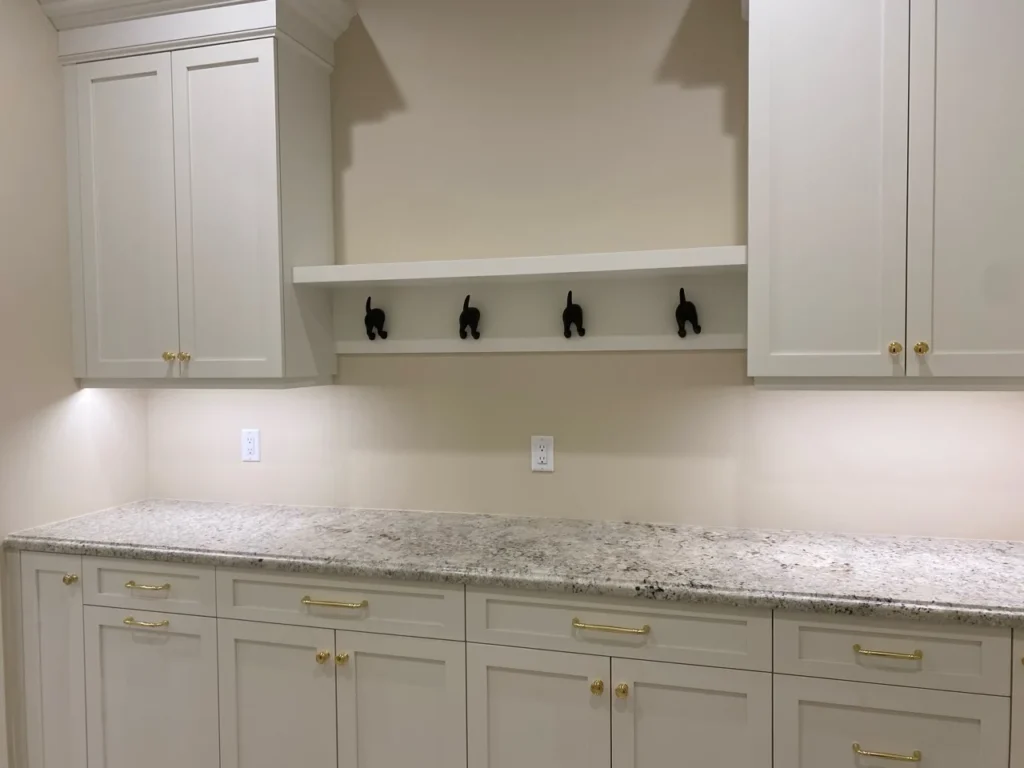 White laundry and mudroom cabinetry with long work surface, drawers and wall hooks