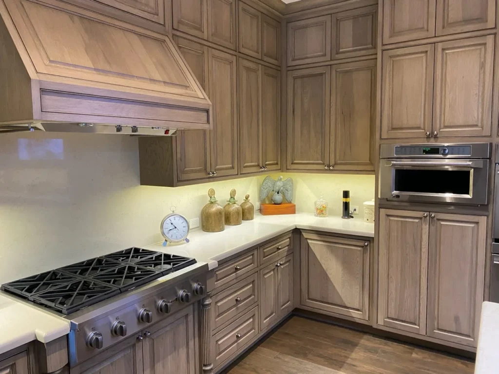Stained manufactured kitchen cabinetry with paneled range hood and integrated appliances
