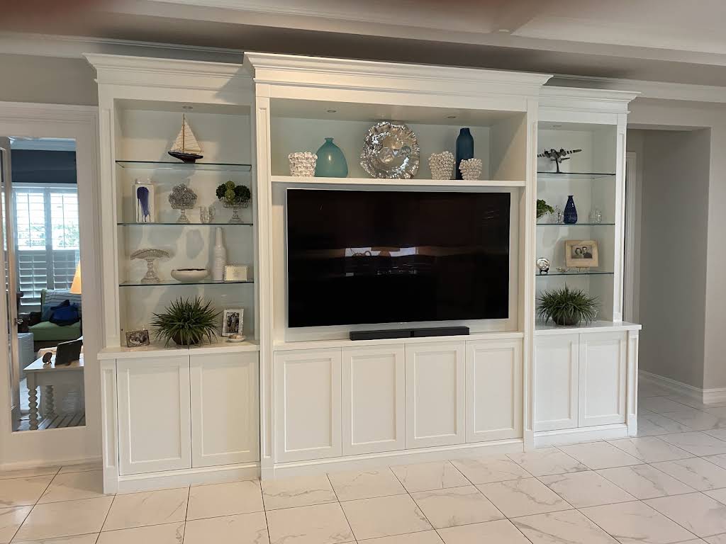 White media wall with illuminated display shelves, integrated television and concealed base storage