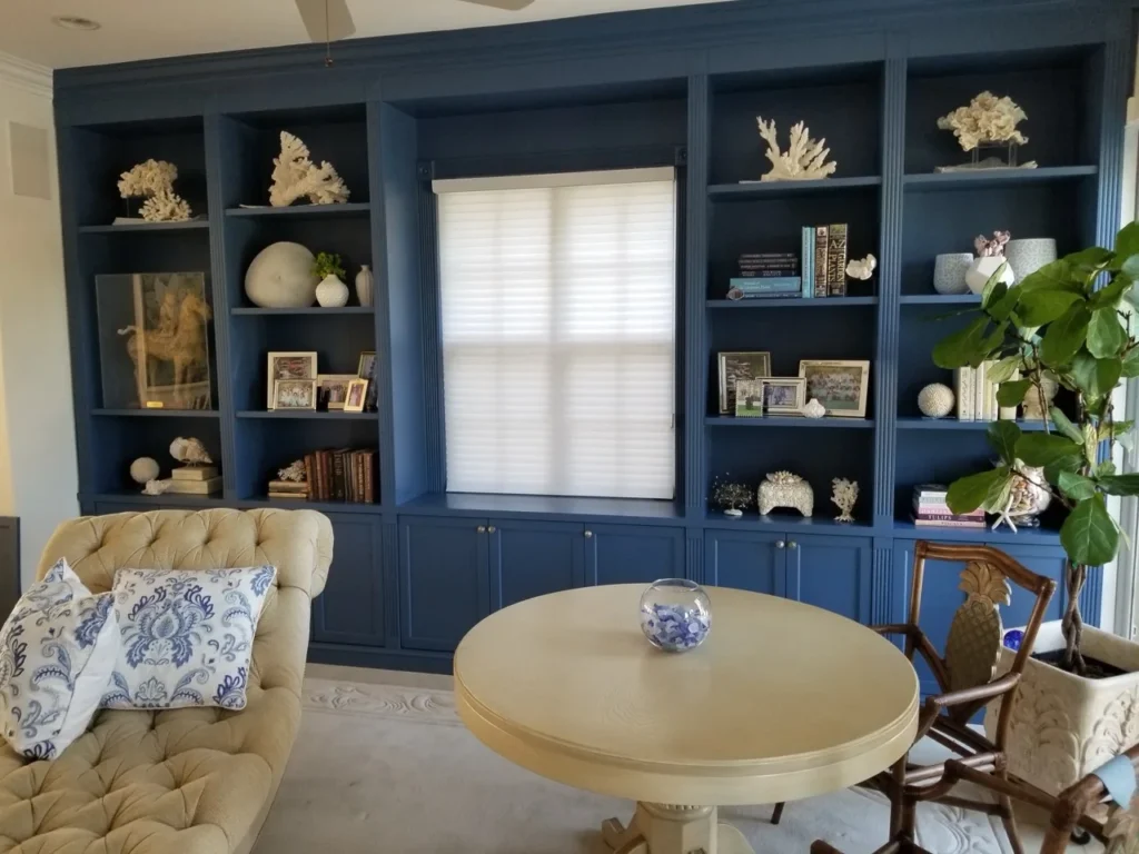 Navy built-in library wrapping a central window with display shelves and base storage