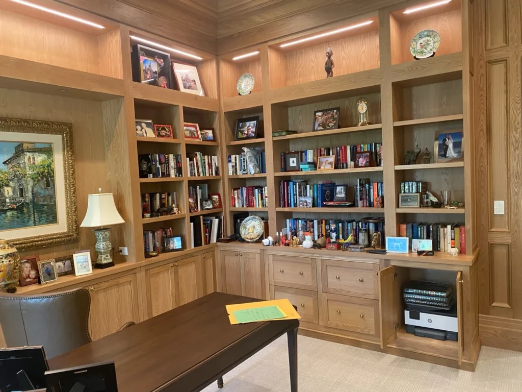 Oak corner home office with wraparound bookshelves, display lighting and base cabinets