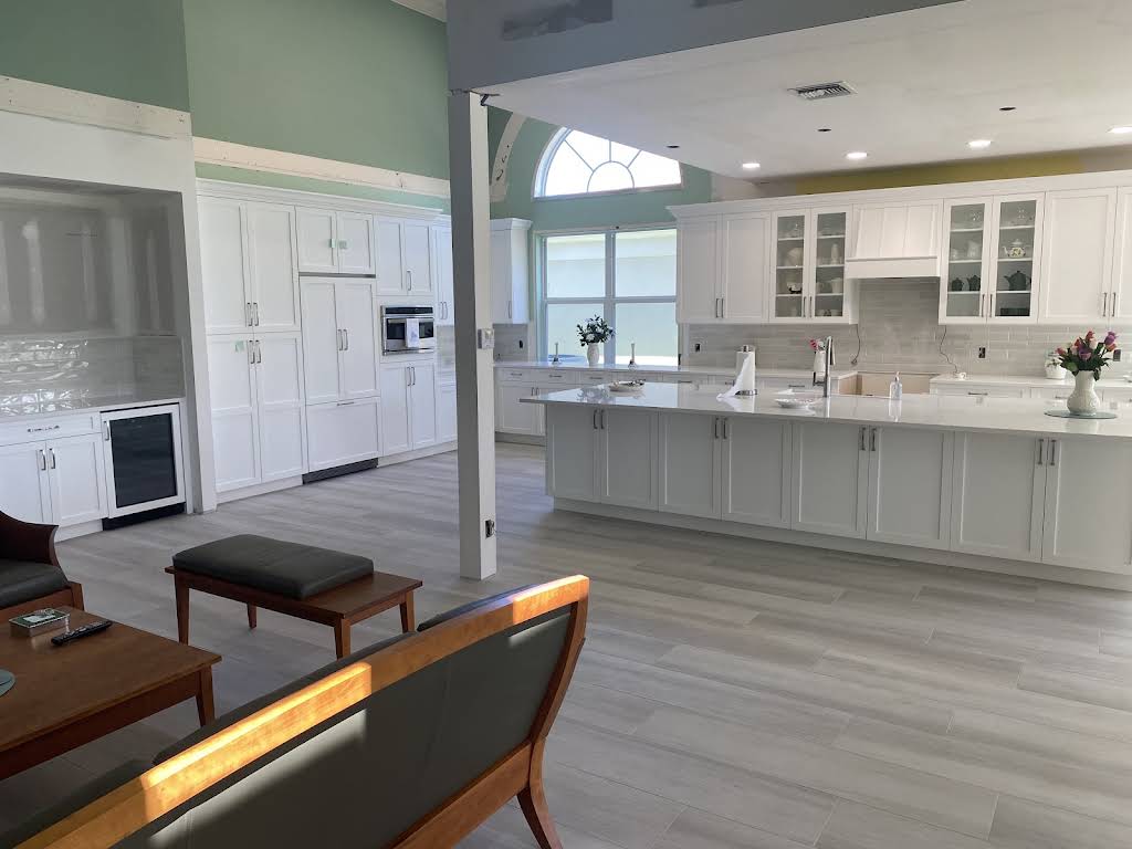 Open-plan white kitchen with a large island and cabinetry extending into the living space