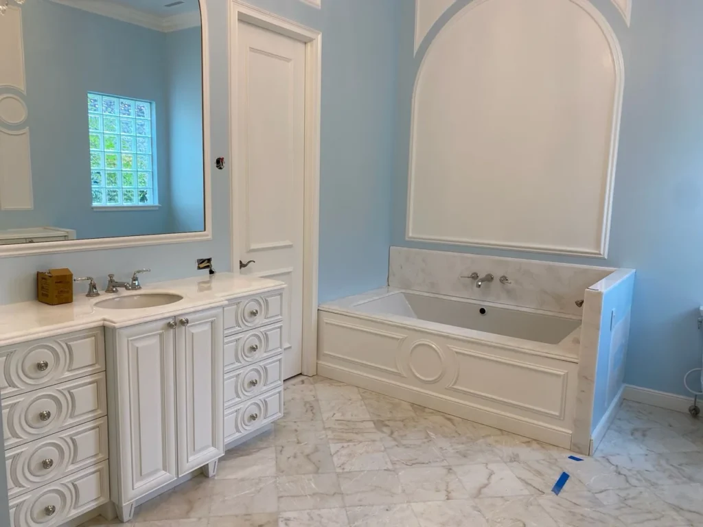 Decorative white bathroom vanity with circular drawer details and matching tub surround