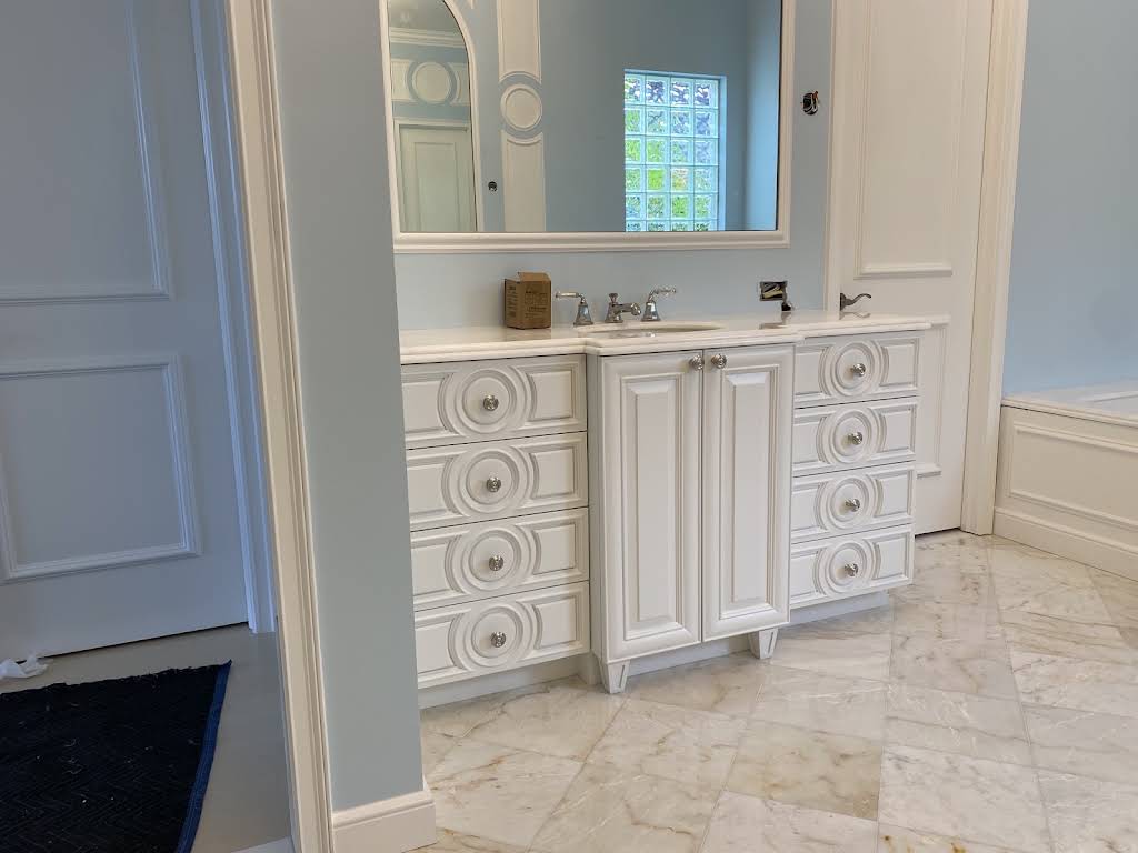 White bathroom vanity with circular drawer details and decorative wall paneling