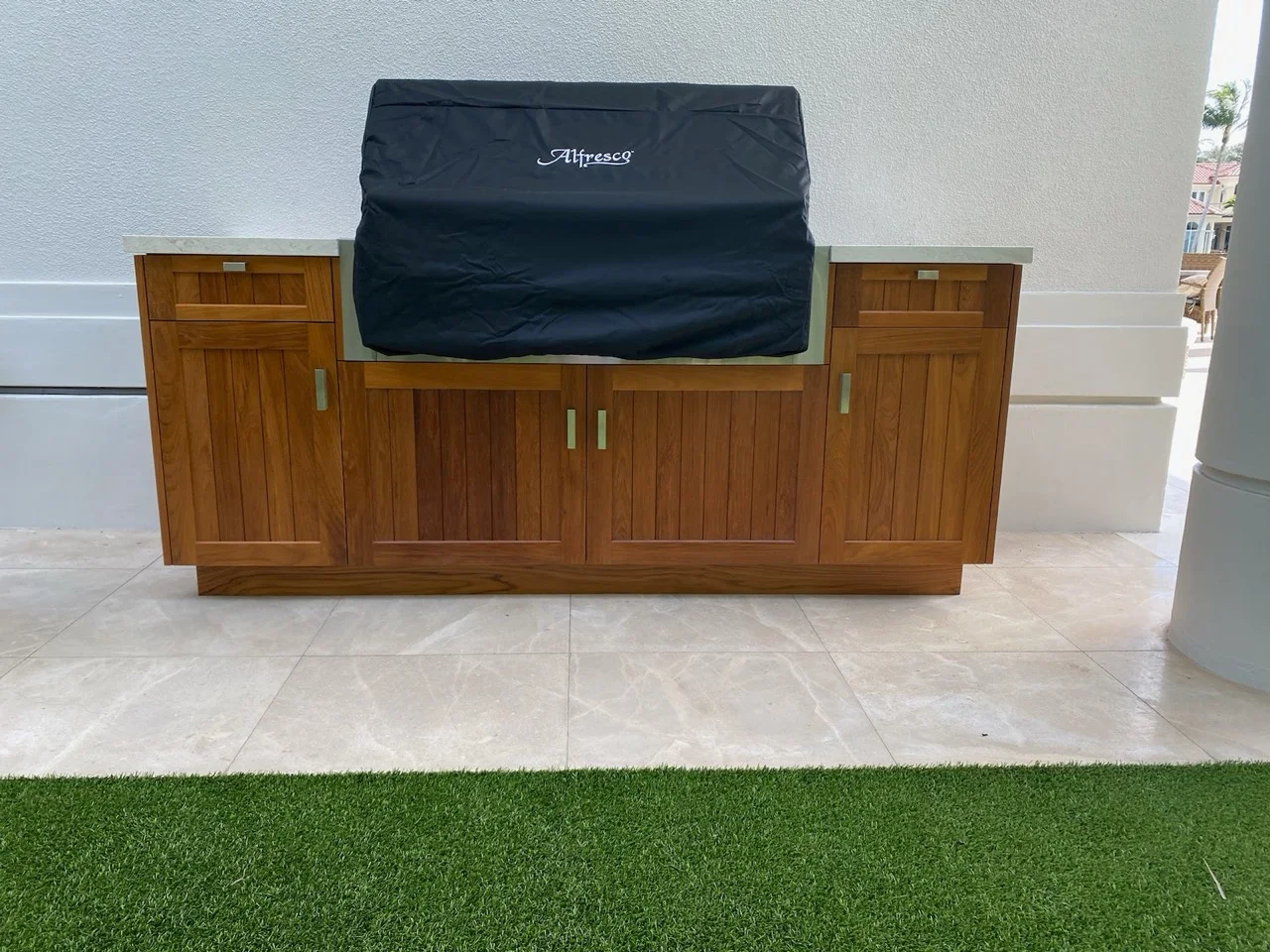 Teak outdoor barbecue cabinet with paneled doors and stone work surfaces