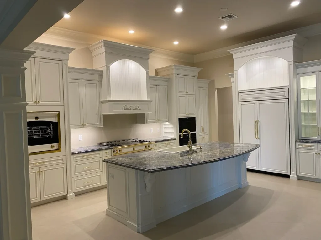 Traditional white kitchen with decorative range hood, tall cabinetry and a stone island