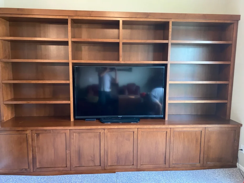 Walnut wall unit with centered television, open bookshelves and paneled base cabinets