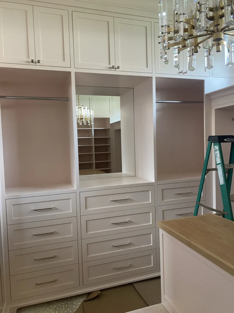 White dressing closet with glass-front wardrobes, drawer island and integrated lighting