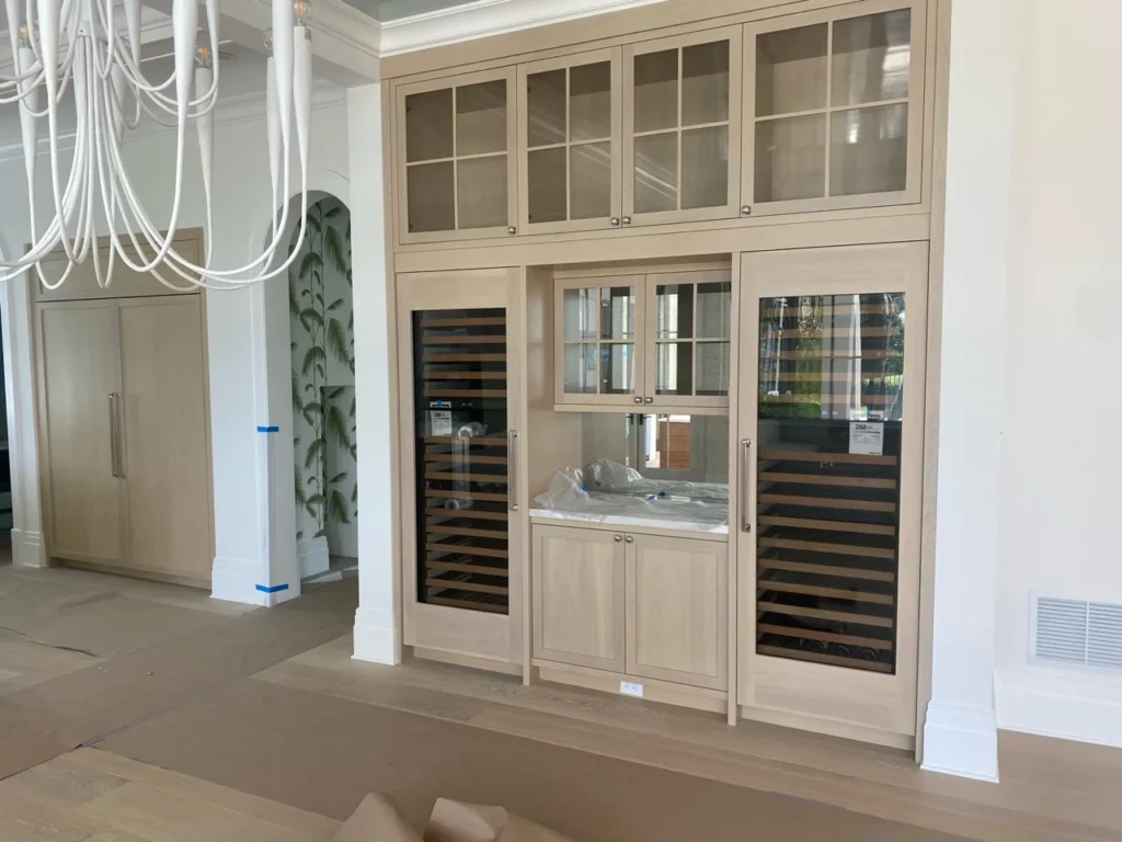 Full-height white wine storage wall with illuminated bottle display and glass cabinets